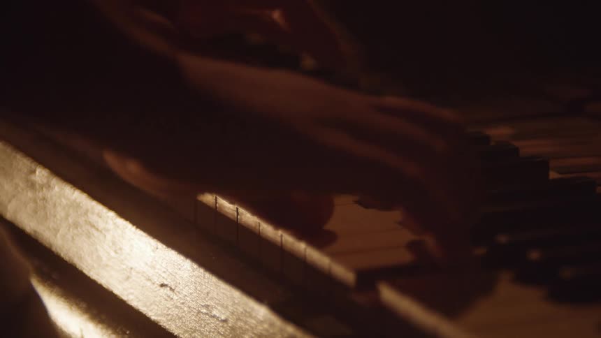 Mans hands press the black and white keys on the keyboard of the piano
