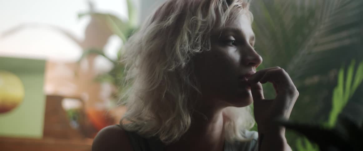 Blonde woman raises head from leaning on hand then turns head