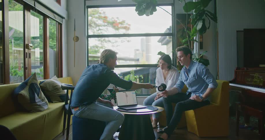 Group of people sitting in the living room gathered around a laptop working on a design