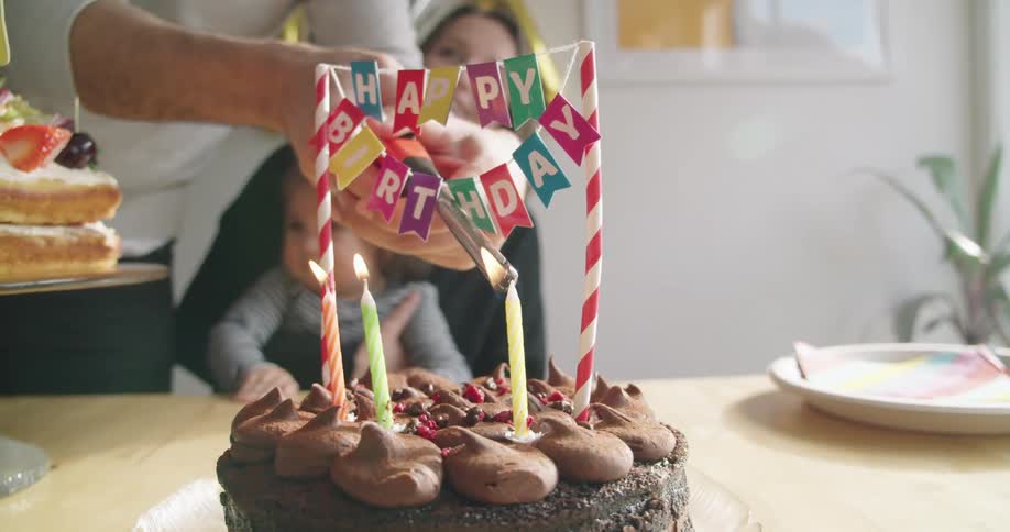 A man is lighting the candles on a birthday cake