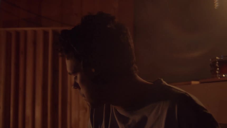 Silhouette of a young man playing drums inside a dimly lit room