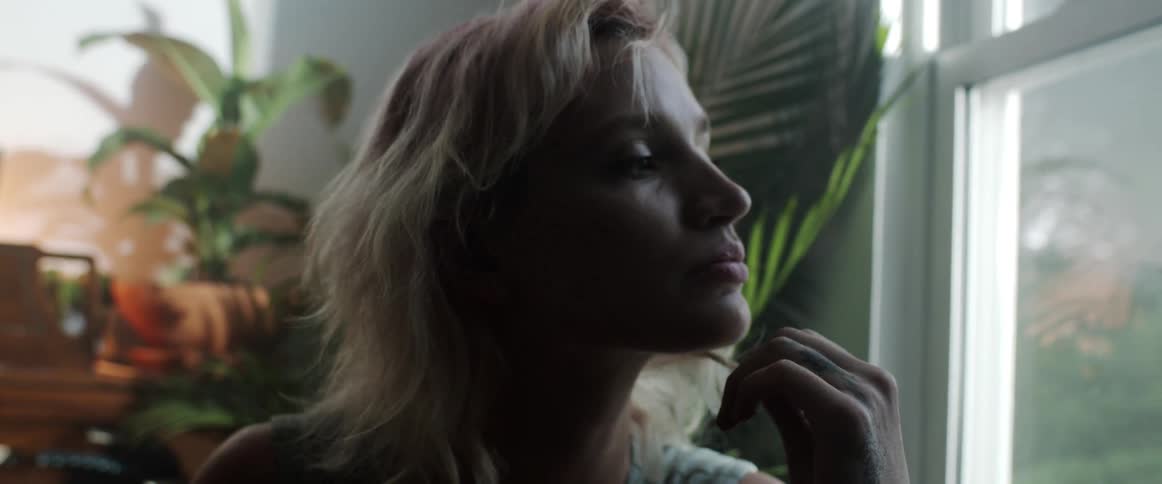 A woman is sitting indoors next to a window in spring