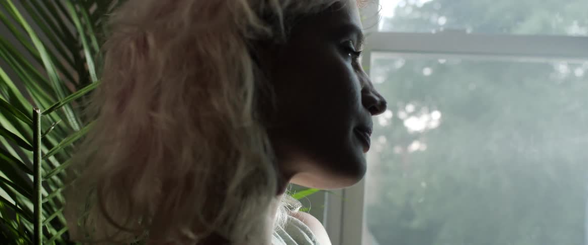 A woman is standing in a room and looking out a window in spring