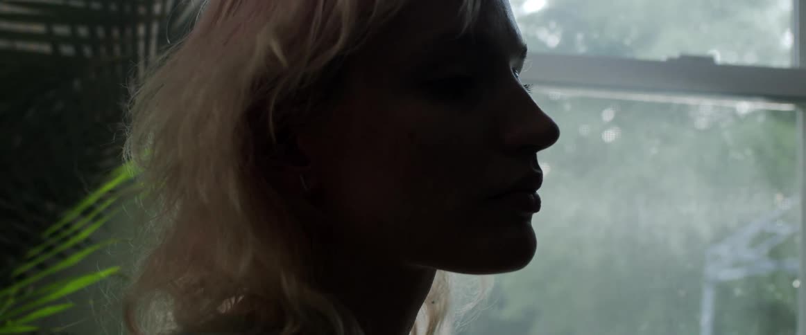 A woman is standing indoors next to a window