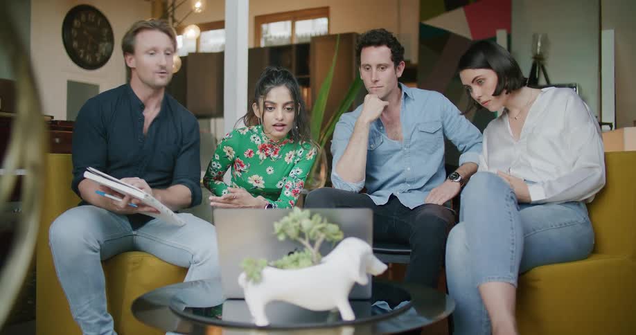 Group of people gathered around a laptop in a work meeting