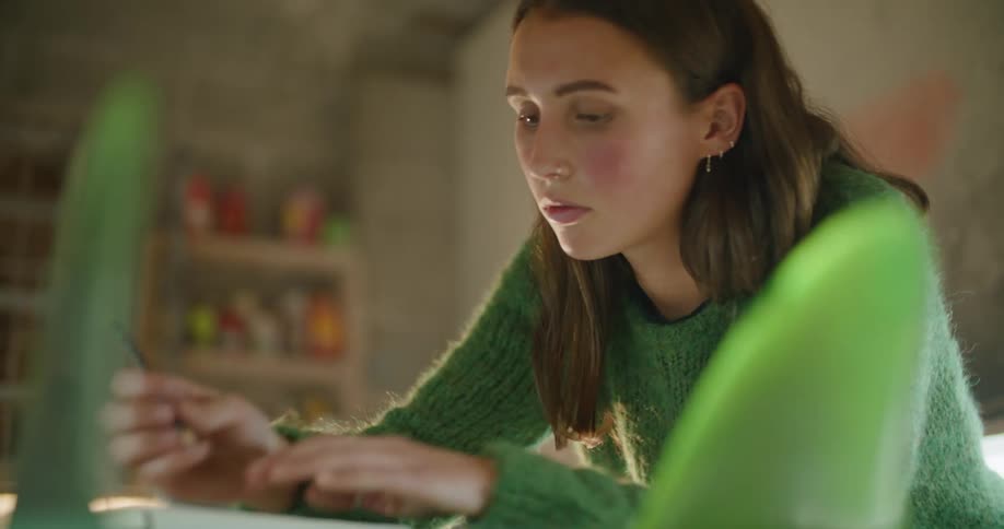 A woman is sitting in a room and writing on paper