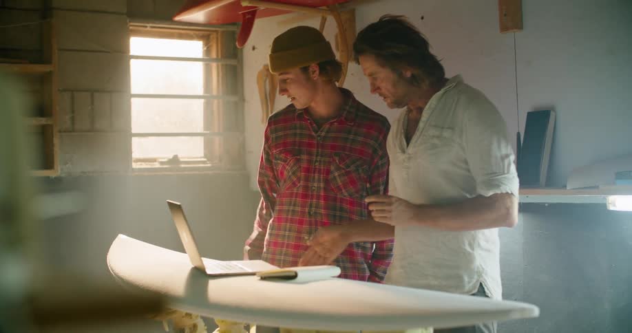 Two men are standing in a garage and talking