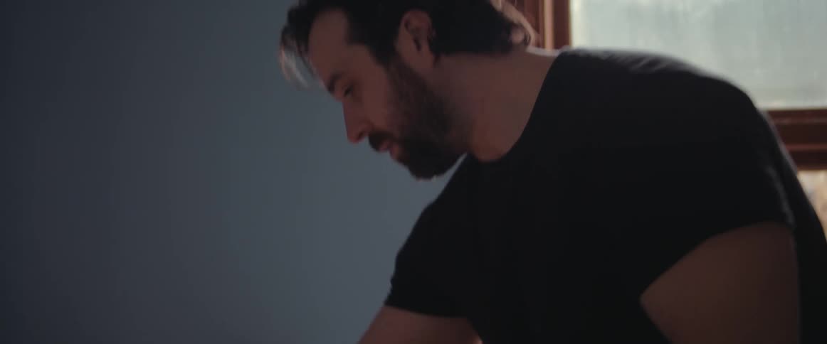 A man gathers papers off of a desk and leaves the room