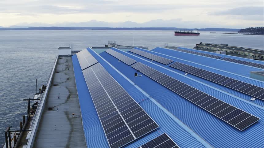 Solar panels installed on the roof of a commercial building near a bay