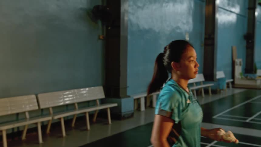 Young woman practicing badminton in an indoors court