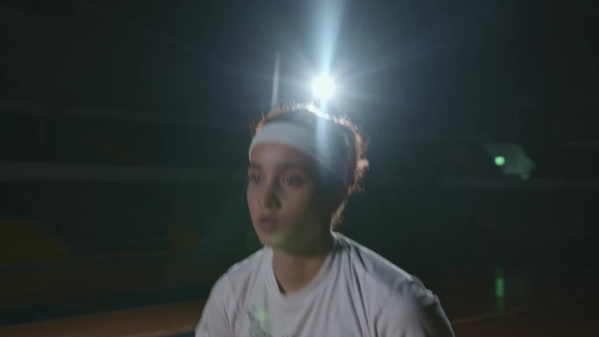 Girl with a white headband and t shirt shoots a basketball in the basketball court