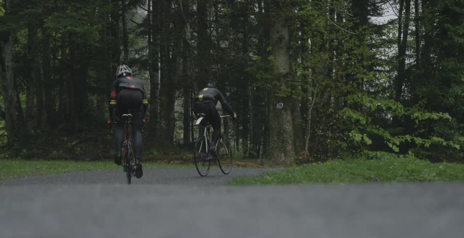 Two cyclists pedaling through a paved trail