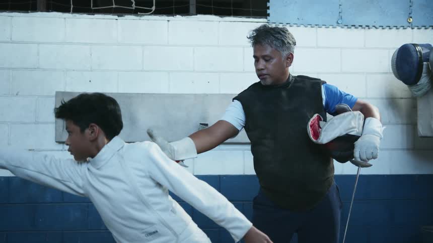 A man instructs a boy in sword fighting