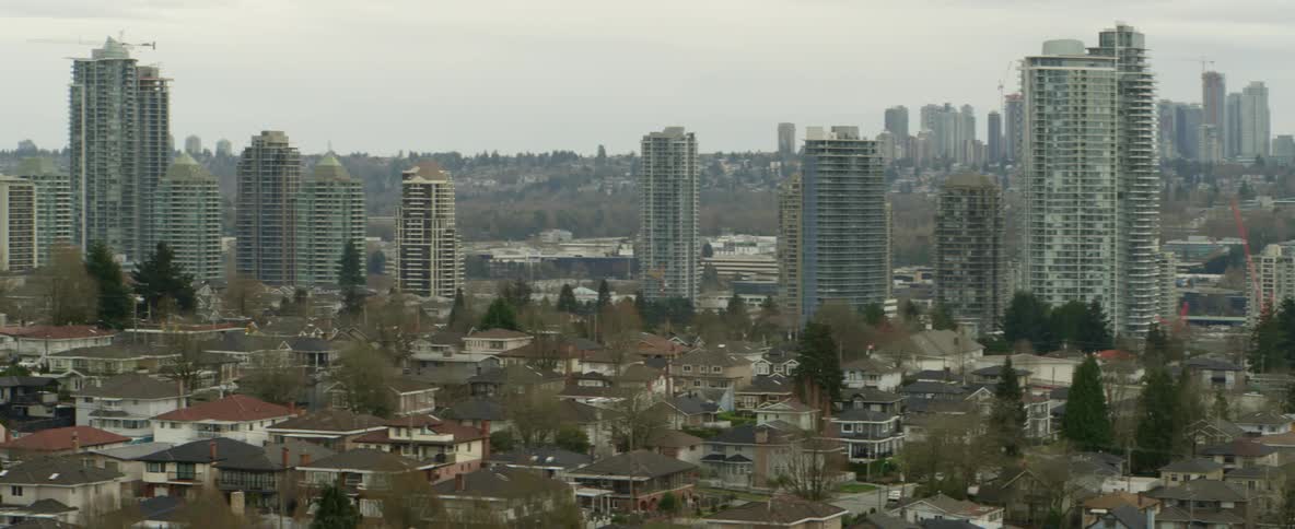 A city with buildings and trees with the sky and clouds in the background