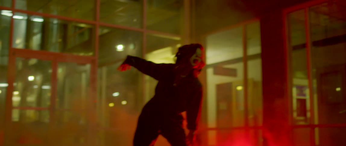 Girl wearing overalls dancing outside a building at night surrounded by smoke