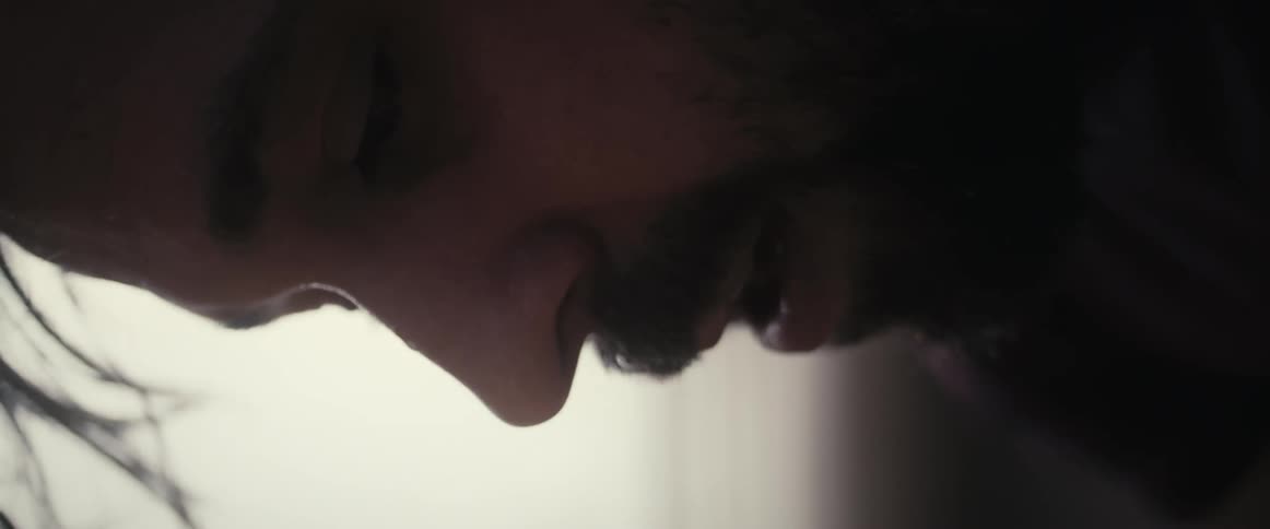 A man bent over looking down and panting