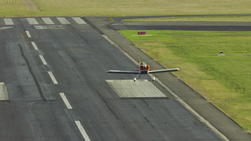 A single engine passenger airplane takes off from a paved airfield before rapidly gaining altitude