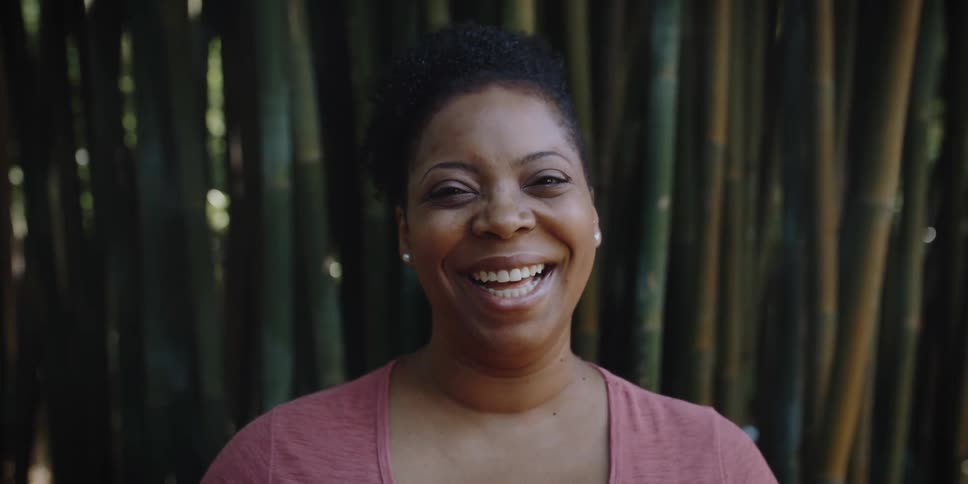 Happy woman standing outdoors looks at the camera while laughing