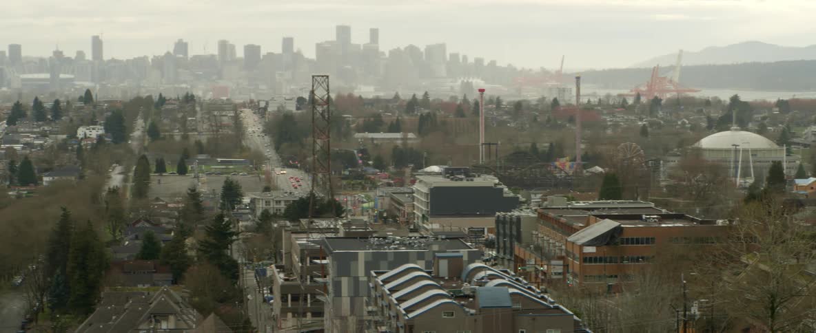 A city with buildings and trees with the sky and clouds in the background