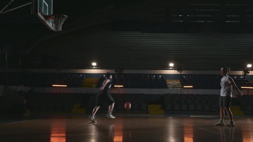 Two people are playing basketball together in a gym