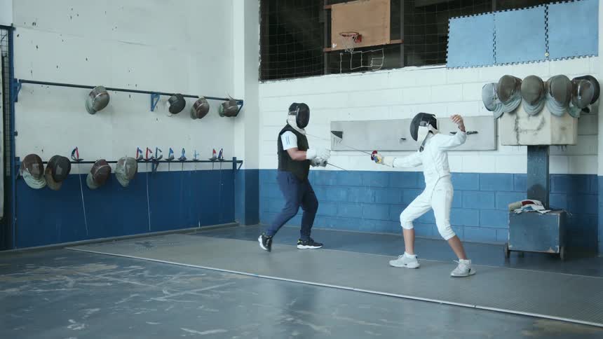 Coach training a teenage girl fencing stances