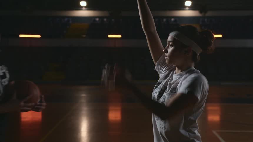 Coach teaching a teenage girl how to throw a basketball