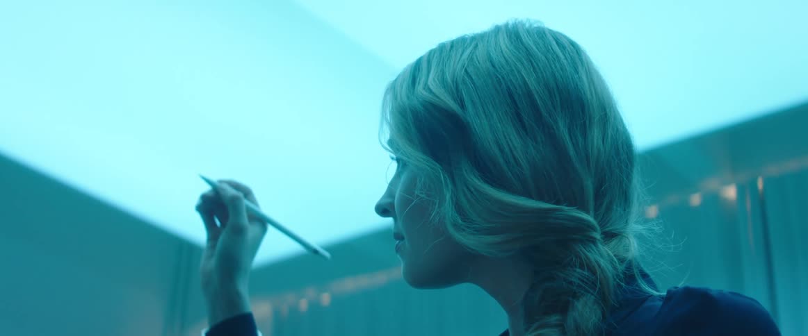 A woman in a room drawing with a stylus with a wall in the background