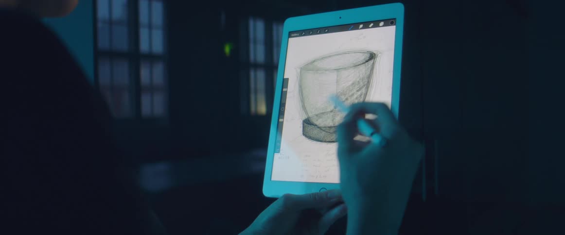 A designer drawing a cup using a stylus on a tablet