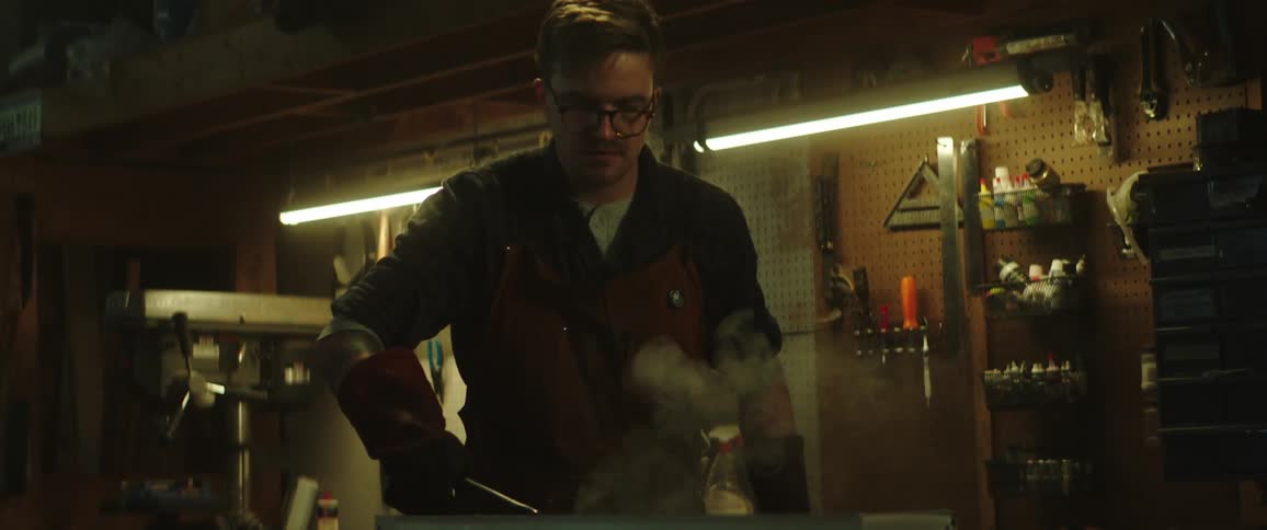 Blacksmith quenching hot metal on an oil bath in the workshop