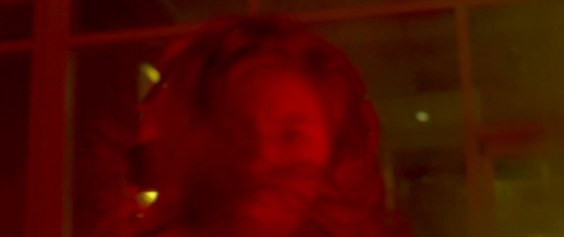 Girl wearing overalls dancing outside a building at night surrounded by smoke and flashing lights