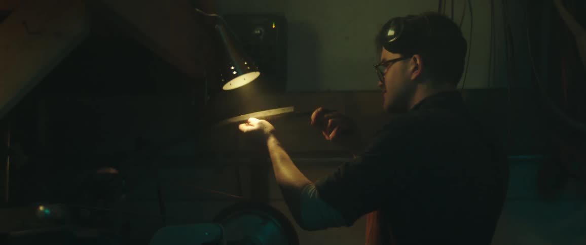 A man checks a blade under the lamp