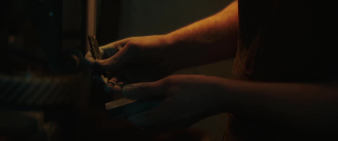 A blacksmith marking a piece of metal inside a dimly lit workshop