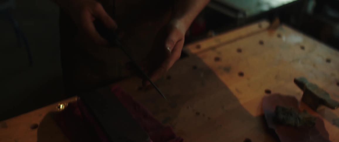 A blacksmith examines a blade