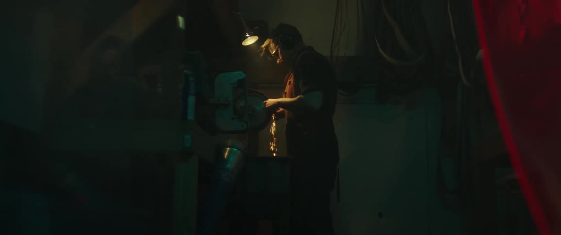 Sparks fly as a man grinds metal on tabletop in his workshop