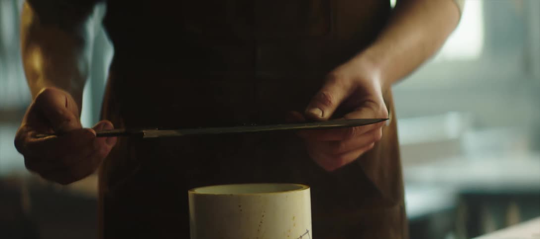 A man soaking the blade of a knife on an oily black liquid