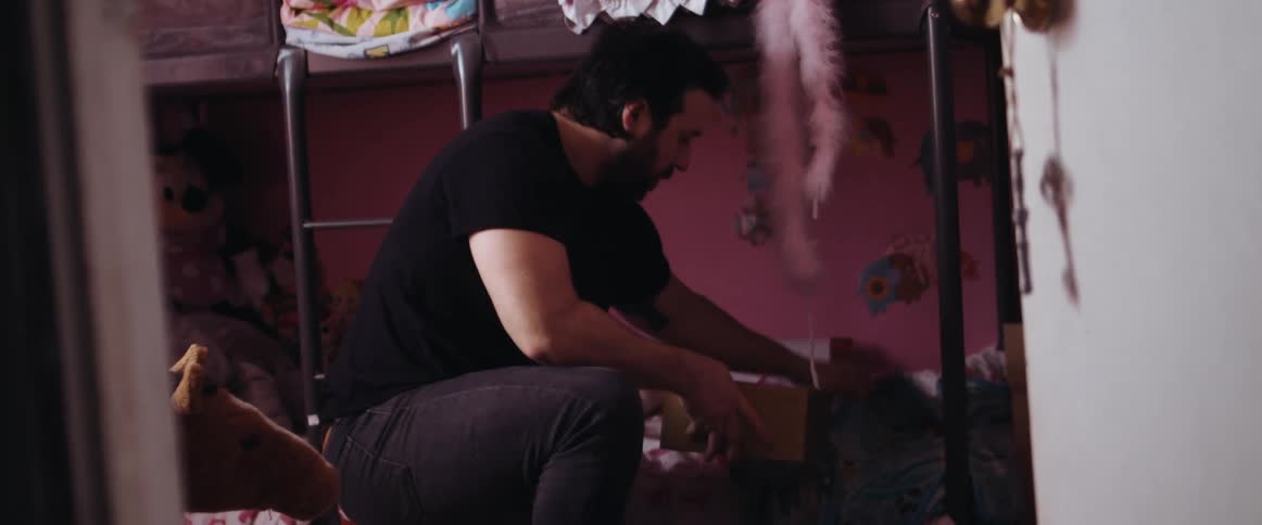 A father cleaning a childs room sorting laundry and putting away toys