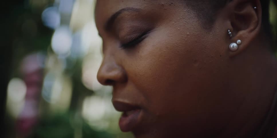 A woman is closing her eyes and sitting outside
