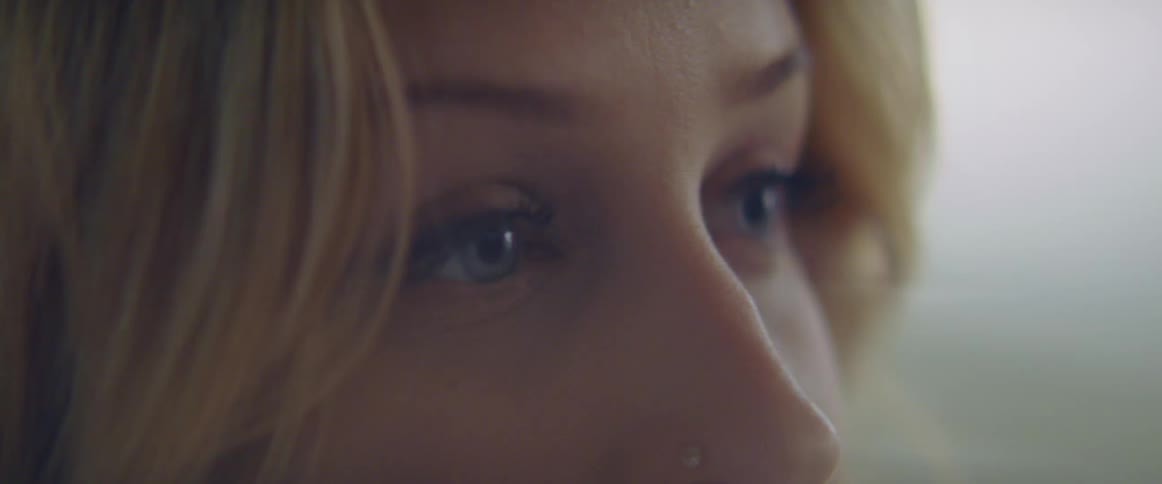 A woman in a room with a nose ring staring off into the distance