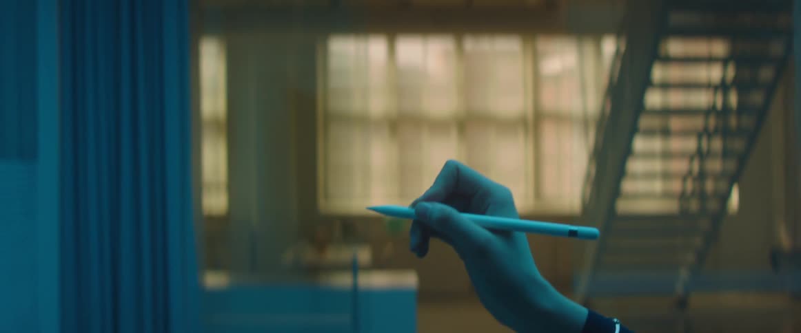 Woman drawing imaginary lines in the air with a pen inside a room under blue lights