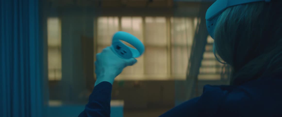 A woman wearing a white vr headset waves a remote around in the air