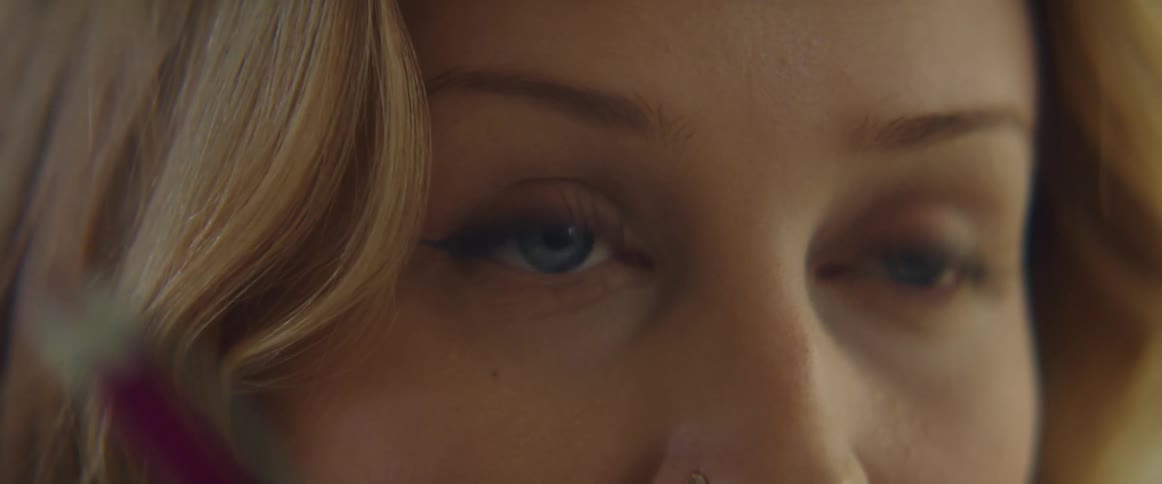 Blonde woman with blue eyes and a nose piercing makes a drawing with a mechanical pencil