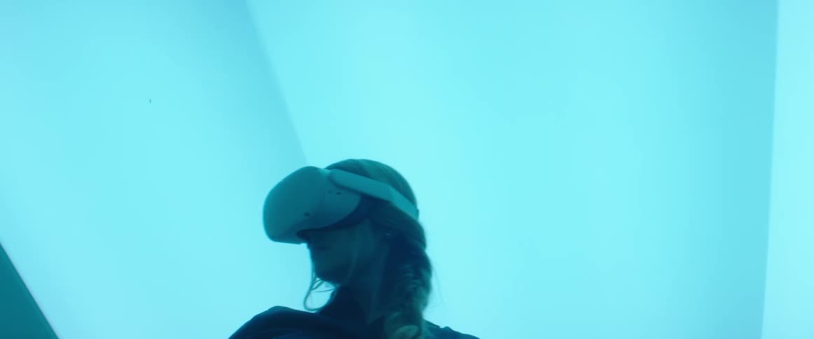 Woman testing virtual reality goggles and controls inside an office