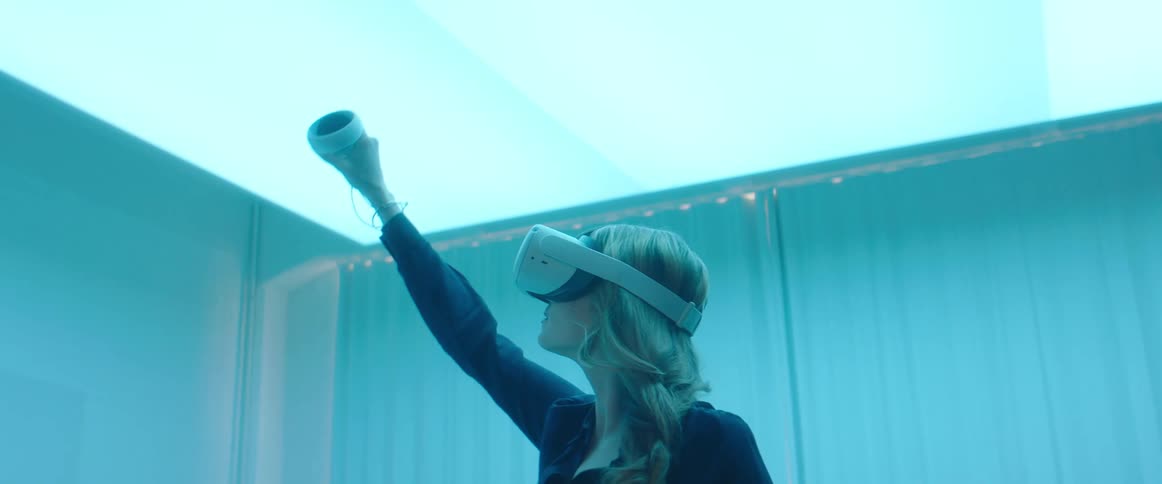 A woman is waving a controller while using a virtual reality headset