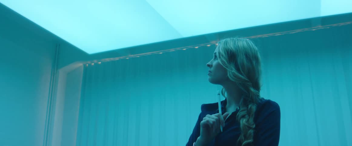 A woman in a room holding a stylus with a wall in the background