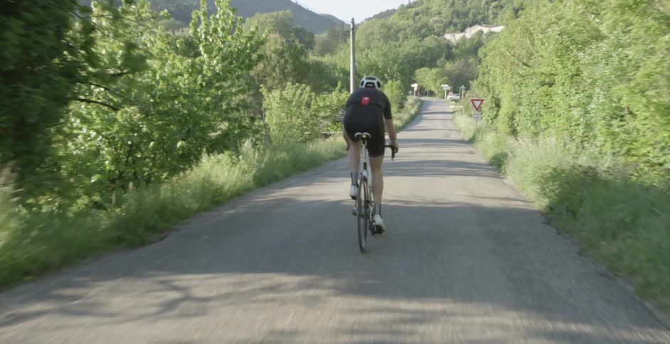 A man is riding a bike down a small road