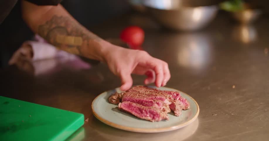 A chef puts meat on a plate