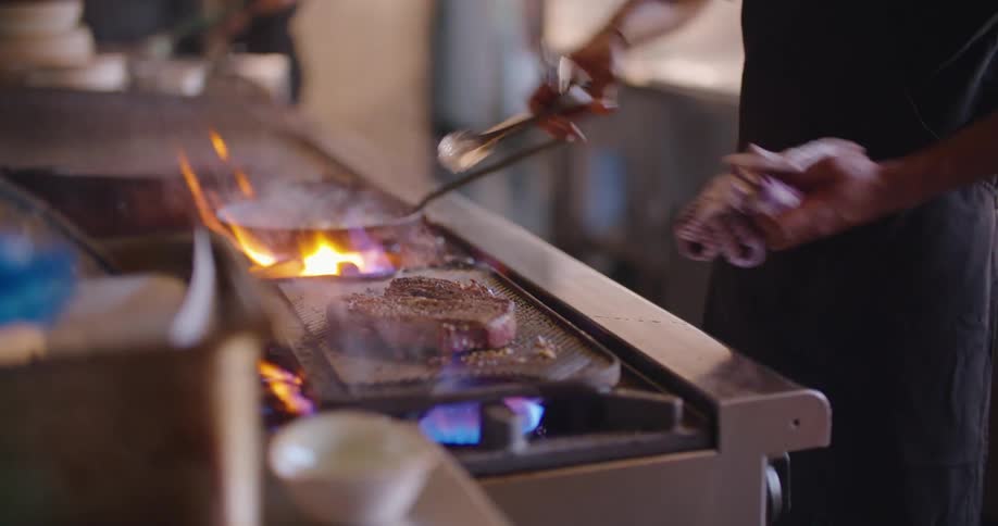 A chef is cooking a steak in the restaurant