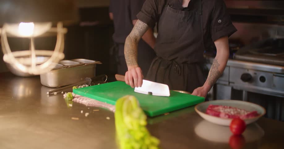Chef talking to a customer while chopping ingredients on the restaurant kitchen