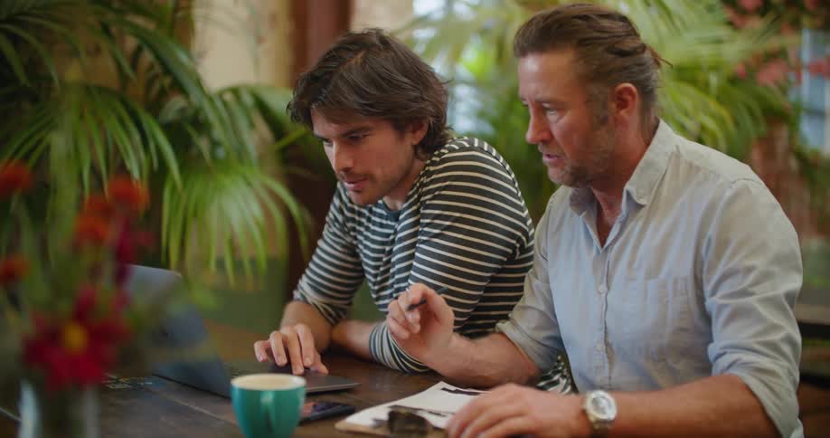 Two men working together on the same laptop
