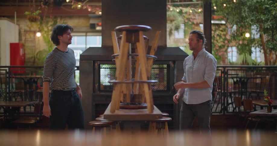 Two restaurant employees bring stools down from the tops of tables before opening
